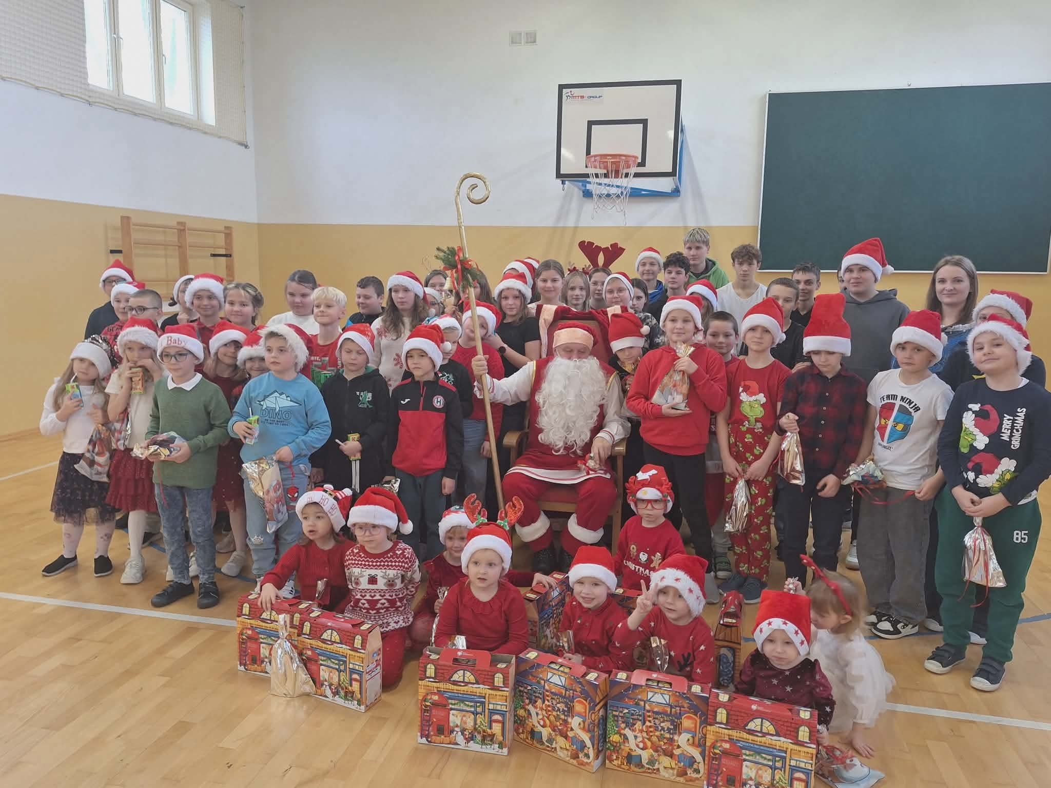 Grupowe zdjęcie wszystkich uczniów z Mikołajem, który siedzi pośrodku trzymając pastorał.